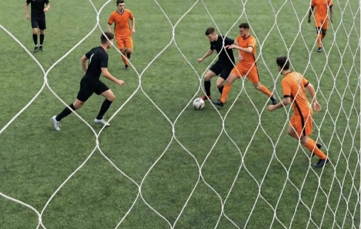 Partido de fútbol con red en primer plano